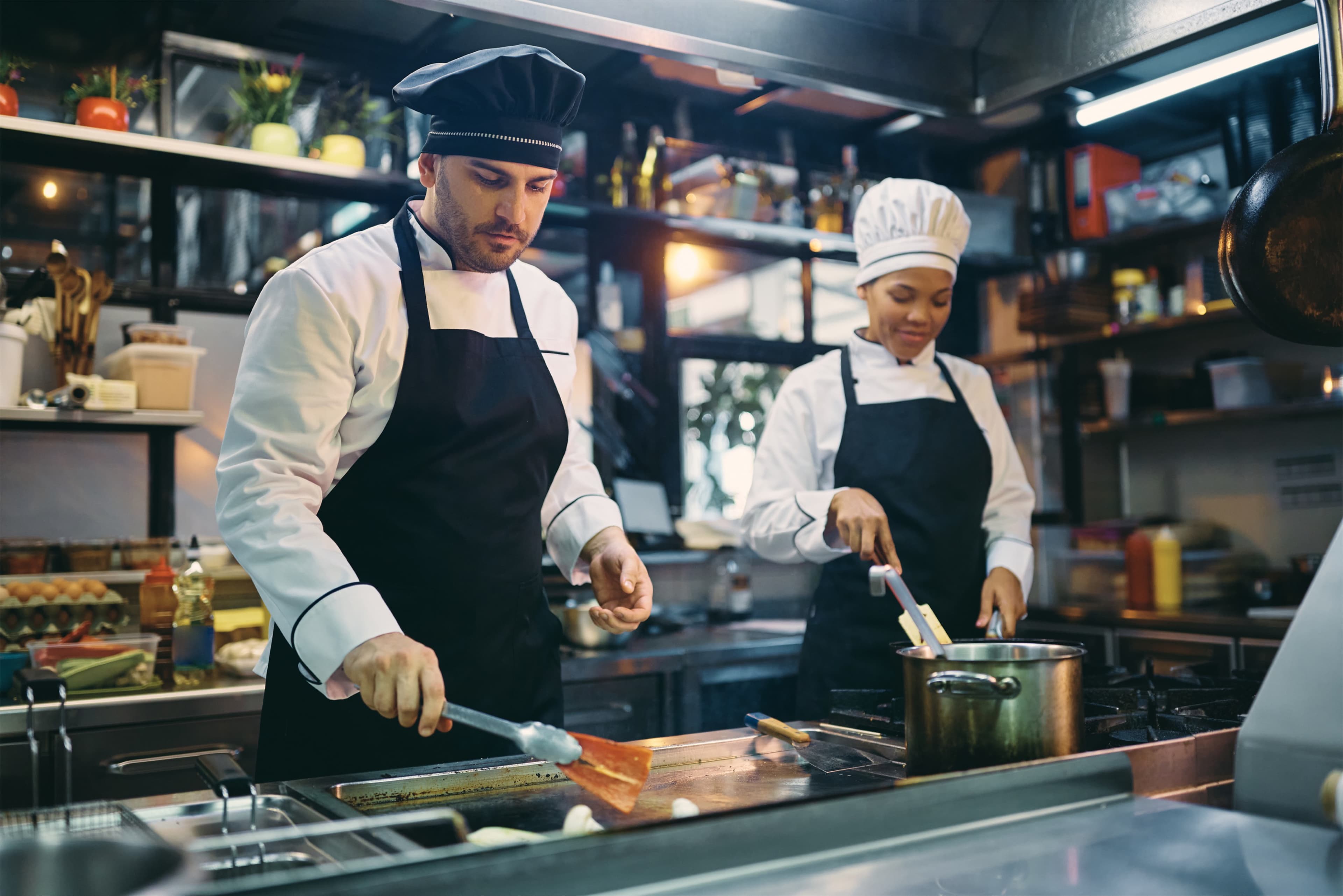 Two chefs prepare food together in a restaurant kitchen.
